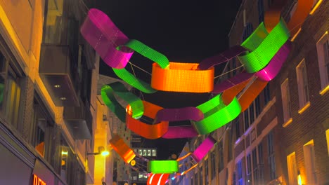 Neon-Coloured-Paper-Chains-Hanging-Above-The-Street-Of-Carnaby-During-Christmas-Night-In-Soho-District,-London