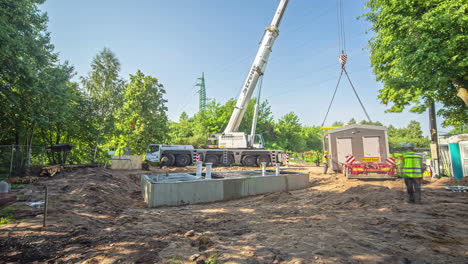 Crane-and-crew-lifting-and-placing-a-work-office-trailer-on-its-foundation---time-lapse