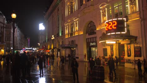 Pan-shot-over-crowded-Piccadilly-Circus-in-London's-West-End-with-neon-signs-mounted-on-the-corner-building-at-night-time