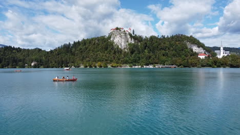 Tiro-De-Dron-Del-Lago-Bled-En-Eslovenia---Dron-Está-Volando-Bajo-Sobre-El-Lago,-Pasando-Por-Un-Bote-De-Remos