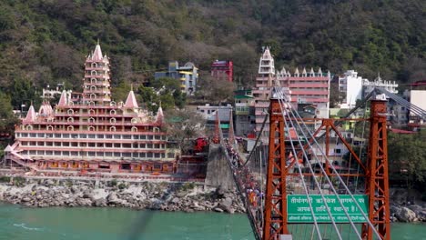 Alter-Hindu-tempel-Am-Ganges-ufer-Mit-Eisenbrücken-führungslinie-Am-Tag-Aus-Einem-Flachen-Winkelvideo-Wird-Am-Trimbakeshwar-tempel-Lakshman-Jhula-Rishikesh-Uttrakhand-Indien-Am-15.-März-2022-Aufgenommen