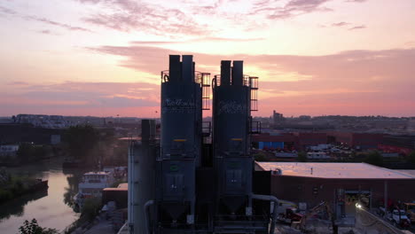 Aerial-View-of-Sunset-Above-Brooklyn-NYC-USA-and-Silos-of-Ready-Mix-Concrete-Plant,-Revealing-Descending-Drone-Shot-60fps