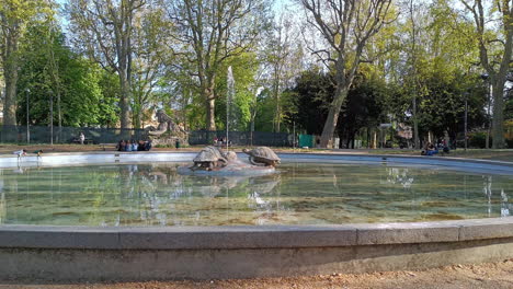 Fountain-of-the-Mermaids-in-Parco-della-Montagnola,-Bologna-with-people-relaxing-in-the-park