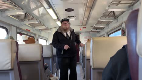Train-conductor-or-guard-walks-through-carriage-checking-tickets