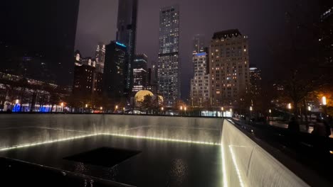 Ground-Zero-9-11-Memorial-Park-at-Night,-Lights-on-Landmark-and-Buildings-in-Lower-Manhattan,-New-York-USA