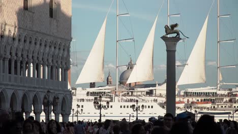 A-large-ship-moves-in-the-background-as-tourists-fill-St-Marks-Square-in-Venice,-Italy
