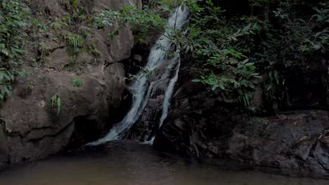 Langsames-Schwenken,-Das-Sich-Von-Der-Mündung-Eines-Wasserfalls-Zurückzieht,-Um-Einen-Kleinen-Teich-Und-Eine-Breitere-Felsige-Umgebung-Im-Tropischen-Bergwald-In-Rio-De-Janeiro-Zu-Enthüllen