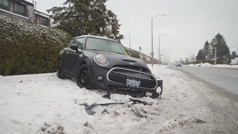 Crashed-car-on-the-sidewalk-beside-a-snowy-road