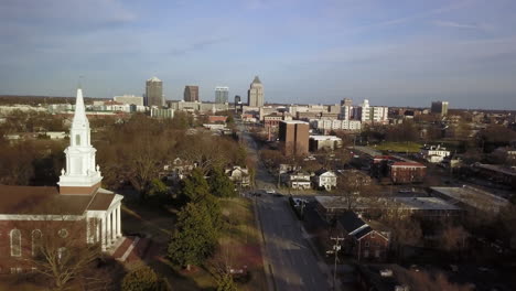 Aerial-shot-flying-toward-Greensboro-North-Carolina-Skyline-with-First-Baptist-Church-of-Greensboro-in-the-foreground