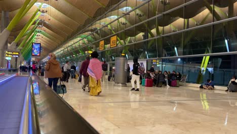 People-walking-towards-their-gate-while-others-wait-for-their-flight-in-the-airport-of-Barajas,-Madrid