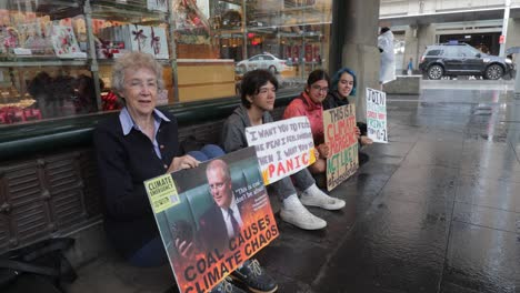 Climate-action,-climate-emergency,-climate-panic,-Scott-Morrison-placard,-young-and-old-peaceful-climate-protestors-in-rainy-Sydney,-locked-down-low-wide-angle-closeup