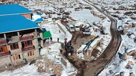 Aerial-shot-of-a-group-of-travellers-getting-down-the-tempo-amidst-the-snowy-winter-spiti-landscape