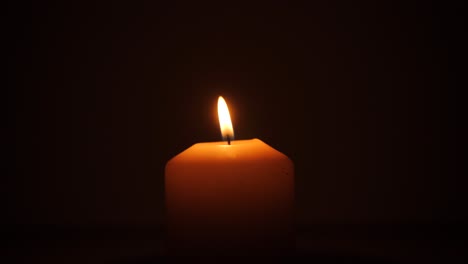 Candle-with-its-orange-flame-in-the-dark