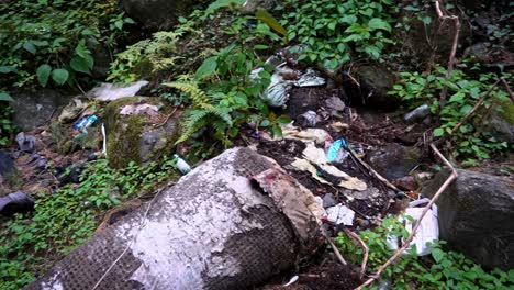 Müll-Verstreut-Auf-Dem-Felsigen-Waldboden-Im-Berg-In-Manali,-Himachal-Pradesh,-Indien---Nach-Unten-Kippen,-Schwenk