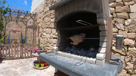Rotisserie-Chicken-rotating-in-a-wood-and-charcoal-fire-brick-bbq-grilling-in-fast-forward