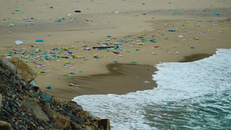 Paradise-sandy-beach-polluted-by-trash-thrown-by-sea-waves