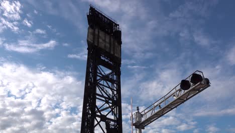 Alter-Rostiger-Stahlturm-Und-Bahnübergang-Im-Zeitraffer-Mit-Flauschigen-Weißen-Wolken-Und-Blauem-Himmel-4k