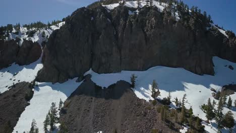 Aerial-close-up-of-a-snow-covered-granite-mountain-protruding-into-the-sky