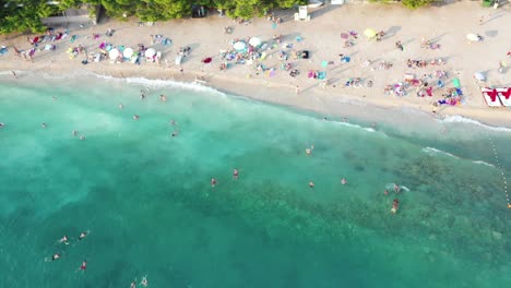 Aerial-top-down-view-of-people-swimming-in-sea,-relaxing-at-the-brach