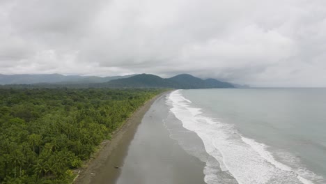 Aerial-shot-of-a-blacksand-beach-during-a-cloudy-day-on-the-Pacific-Coast,-Colombia