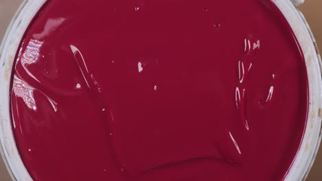 Close-up-of-woman-opening-plastic-paint-can-to-reveal-red-paint