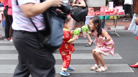 Young-Children-Playing-With-Toy-Bubble-Guns-At-A-Crowded-Market