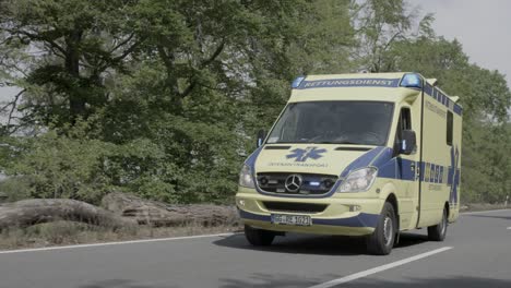 Ambulance-using-flashing-signal-passing-on-highway,-slow-motion