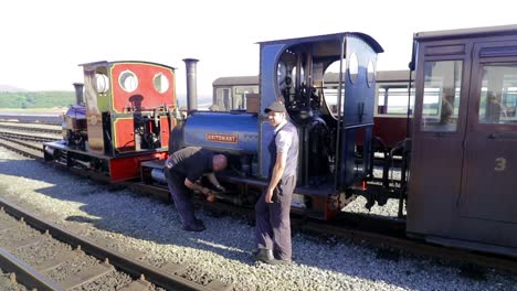 Ffestiniog-Railway---two-engineers-prepare-BRITOMART-narrow-gauge-steam-engine-for-departure-at-Porthmadog-Harbour-Railway-Station,-Snowdonia,-Wales---bald-man,-man-in-cap,-SLOMO-60fps