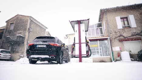 Car-on-small-gas-station-in-snowy-winter-during-petrol-refueling