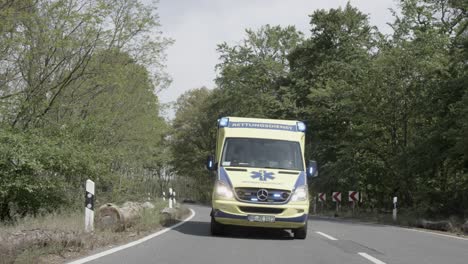 Front-view-on-ambulance-driving-on-forest-road,-slow-motion-dolly-shot
