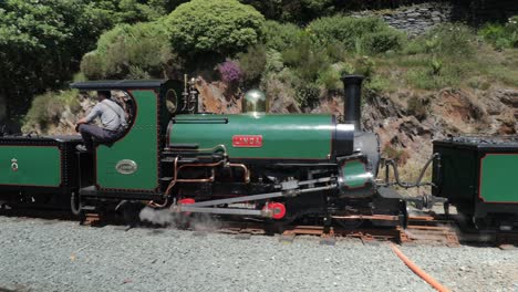Linda---Blanche-narrow-gauge-steam-trains-built-1893-steam-out-of-Tan-y-bwlch-station,-Ffestiniog-Railway,-Snowdonia,-Wales-pulling-tourist-carriages,-SLOMO-60fps