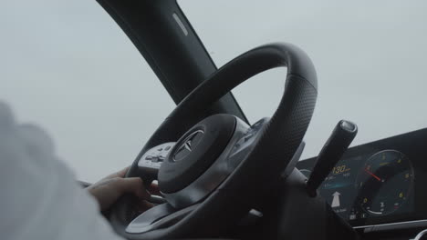 Modern-car-interior,-hand-on-steering-wheel-and-dashboard-close-up