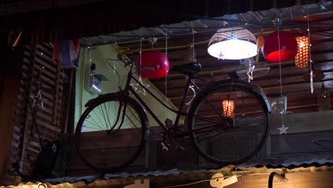 Una-Vieja-Exhibición-De-Bicicletas-En-El-Fondo-De-Tailandia-Con-Luces-Navideñas-Y-Luces-De-Techo-Sobre-El-Techo-De-La-Casa---Primer-Plano