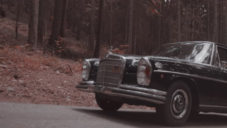 Vintage-Mercedes-Benz-300-SE-driving-on-forest-road,-tracking-shot