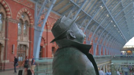 Man-holding-hat-to-head---Betjeman-in-St-Pancras,-London---SLOMO-60fps