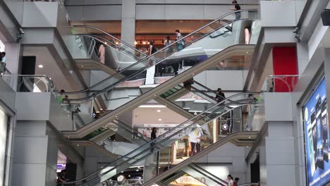 People-taking-escalator-at-MBK-Shopping-Center-Bangkok,-Low-angle-static