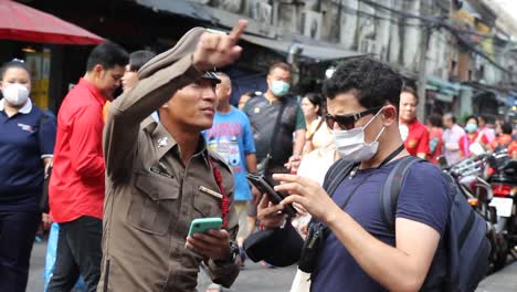 Asiatischer-Mann-Mit-Gesichtsmaske,-Der-Den-Polizisten-Um-Anweisungen-Bittet