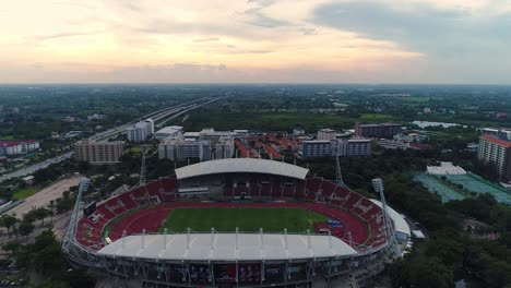 Thammasat-University-main-stadium-bird’s-eye-view-by-drone-seeing-the-sky-with-sunset,-Thailand