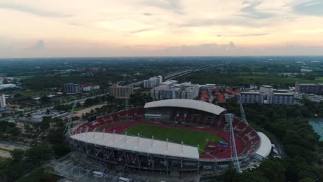 Drone-flying-over-football-stadium-during-sunset