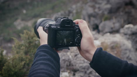 Close-up-on-hands-holding-Sony-A-7iii-camera-while-taking-picture-of-landscape