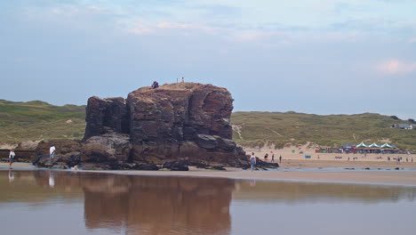 People-play-and-gather-around-Chapel-Rock-at-Perranporth-Beach