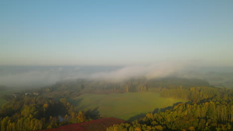Aerial-morning-flight-over-beautiful-field-and-forests-with-log-foggy-clouds