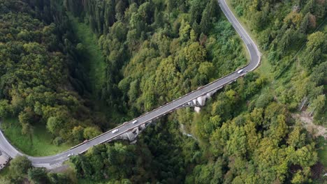 Aerial-top-down-shot-of-spectacular-bridge-with-driving-cars-on-road-and-deep-forest-ravine-in-summer