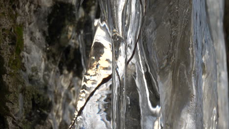 Ice-formation-on-mountain-wall-inside-a-frozen-glacial-cave,-close-up-tilting-down