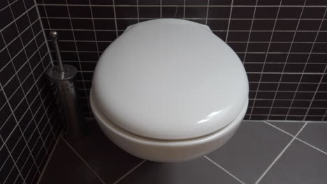 Toilettenschüssel,-Toilette-In-Modernem-Badezimmer-Mit-Schwarzen-Und-Grauen-Fliesen,-4k-Uhd,-Kranschuss,-Kippbewegung-Nach-Unten