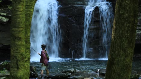A-young-man-fishes-below-Seneca-Falls,-a-large-waterfall-located-along-Seneca-Creek,-within-the-Spruce-Knob-Seneca-Rocks-National-Recreation-Area-in-West-Virginia