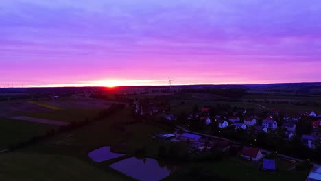 Panorama-Bei-Sonnenuntergang-Fliegt-Eine-Drohne-über-Seen,-Wiesen-Und-Häuser
