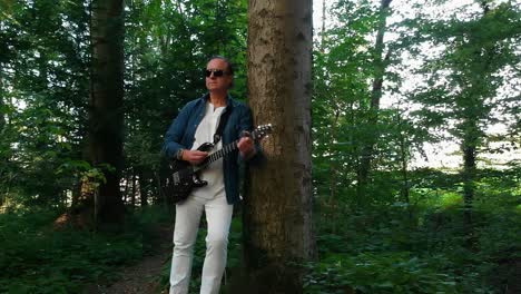 a-male-professional-musician-playing-guitar-in-the-woods