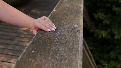 a-young-girl-has-put-her-hand-on-the-railing-of-the-bridge-on-the-hand-has-an-engagement-ring