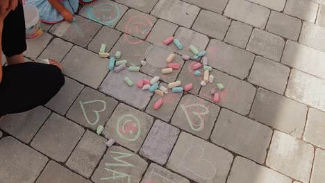 a-mother-and-her-child-draw-with-chalk-on-the-ground-in-front-of-their-home